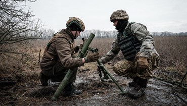 جنود أوكرانيون يعدلون أنبوبًا لقذائف هاون قرب خط المواجهة في منطقة دونيتسك (31 ك2 2023، أ ف ب). 
