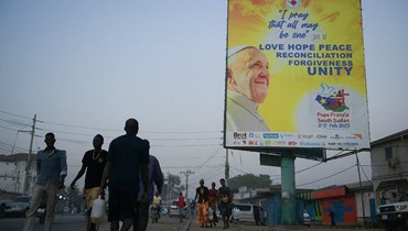 اشخاص يمرون قرب لافتة للبابا فرنسيس في جوبا، بينما تستمر الاستعدادات قبل زيارته لجنوب السودان (31 ك2 2023، أ ف ب). 