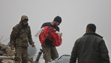 رجل سوري يحمل جثّة رضيع قُتل في زلزال ضرب بلدة جندريس بريف مدينة عفرين شمال غرب سوريا (أ ف ب).