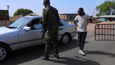عنصر أمن يكلّم سائقا عند حدود بوركينا فاسو في باجا شمال غانا (6 ك2 2022، أ ف ب). 