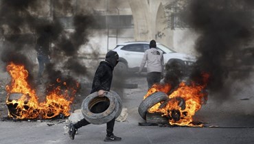 فلسطينيون يحرقون الإطارات لقطع الطريق المؤدية إلى أريحا بالضفة الغربية المحتلة بعد مداهمة القوات الإسرائيلية للبلدة (6 شباط 2023، ا ف ب). 