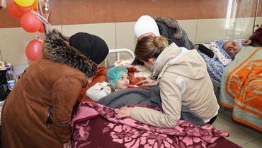 عقيلة الأسد خلال زيارتحها أطفالاً مصابين جرّاء الزلزال في أحد مستشفيات حلب (أ ف ب).
