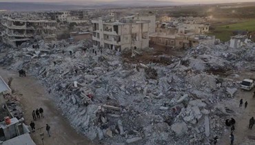 أشخاص يمرون قرب ابنية منهارة من جراء زلزال في بلدة جنديريس بمحافظة حلب في سوريا (9 شباط 2023، أ ب).