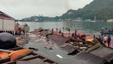  أشخاص يقفون على أسطح متاجر منهارة في الميناء بعد زلزال بقوة 5.1 درجة في جايابورا، مقاطعة بابوا الشرقية بإندونيسيا (أ ف ب). 