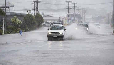 سيارات تعبر طريقاً غمرتها السيول في مدينة وانجاري شمال نيوزيلندا حيث يضرب الإعصار غابرييل (12 شباط 2023، أ ب). 