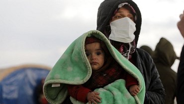 ناجية من زلزال سوريا تحمل طفلاً في مدينة جندريس المنكوبة (أ ف ب).