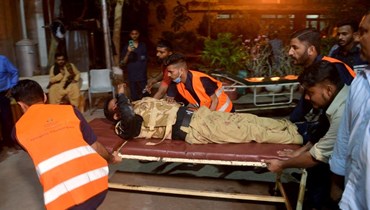 متطوعون ينقلون شرطياً مصاباً إلى مستشفى في أعقاب هجوم على مجمع للشرطة في كراتشي (أ ف ب). 