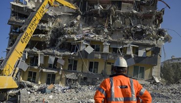 أحد رجال الإغاثة والإنقاذ يقف أمام مبنى مدمّراً في ولاية هاتاي التركية (أ ف ب).