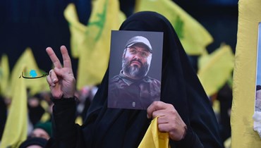 سيدة ترفع صورة القائد العسكري في "حزب الله" عماد مغنية خلال احتفال حزبي في الضاحية الجنوبية (نبيل اسماعيل).
