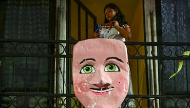 امرأة في شرفتها تشاهد كرنفال "Los huehues madrugadores" في بلدية توتولاك، المكسيك (أ ف ب). 