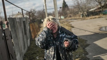 امرأة تبدي رد فعل على صوت القصف بينما وقفت خارج منزلها في قرية تشاسيف يار قرب باخموت (4 آذار 2023، أ ف ب). 