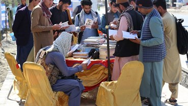 زوار يتصفحون كتبا في كشك خلال معرض للكتاب في جلال أباد (7 آذار 2023/ أ ف ب). 