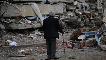 رجل يسير بين حطام المباني المنهارة في كهرمان مرعش بعد شهر من وقوع زلزال هائل في جنوب شرق تركيا (أ ف ب). 