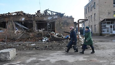 نساء يمرن قرب مصنع لتجهيز اللحوم دمره القصف الروسي في فوفتشانسك بمنطقة خاركيف (9 آذار 2023، أ ف ب). 
