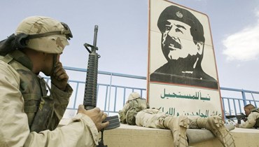 عنصر من مشاة البحرية الأميركية بالقرب من صورة للديكتاتور العراقي صدام حسين في ملعب ببغداد عام 2003 (أ ف ب).