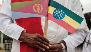 صورة ارشيفية- رجل يحمل العلمين الإريتري (الى اليسار) والإثيوبي بينما ينتظر وصول رئيس إريتريا إلى مطار غوندار شمال إثيوبيا (9 ت2 2018، أ ف ب).