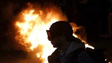 متظاهر يقف بجانب حريق خلال تظاهرة في باريس (أ ف ب). 