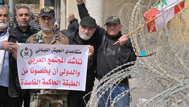 عسكريون متقاعدون وسط الأسلاك الشائكة يرفعون لافتات تدعو إلى تخليص البلد من الطبقة السياسية الفاسدة (نبيل اسماعيل).