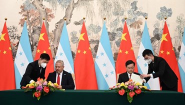 وزير خارجية هندوراس إدواردو إنريكي رينا  ووزير الخارجية الصيني تشين جانج يرفعان نخباً عقب إقامة العلاقات الديبلوماسية بين البلدين (أ ف ب).
