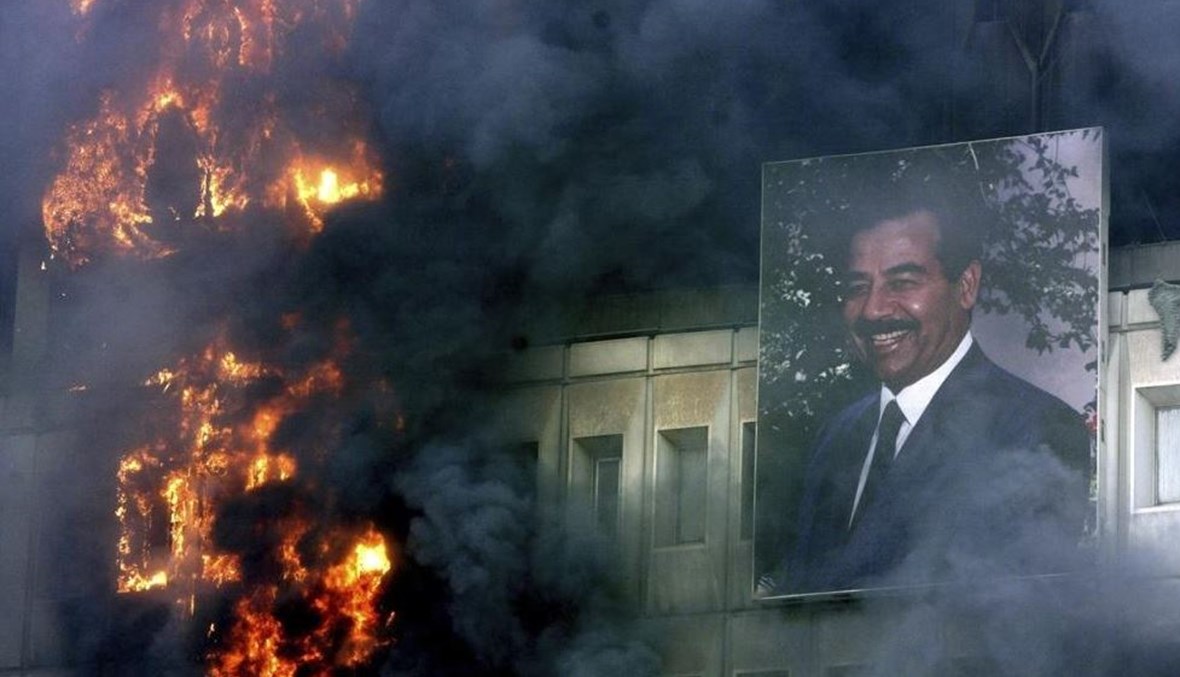 صورة لصدام حسين لا تزال معلّقة على مبنى وزارة النقل والاتصالات المحترق في بغداد، 9 نيسان 2003 (أ ف ب). 