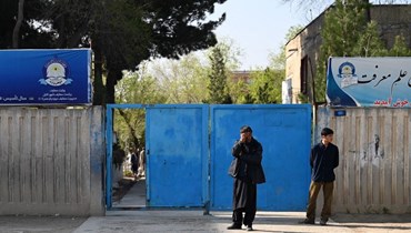 رجال أفغان يقفون عند بوابة مدخل مدرسة في كابول (أ ف ب).