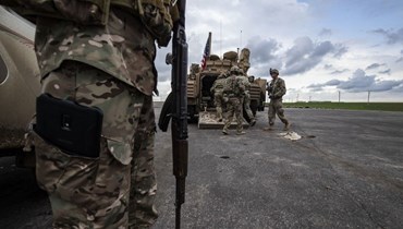  أفراد قوات سوريا الديمقراطية وجنود أميركيين بالقرب من عربة عسكرية مدرعة على مشارف رميلان في محافظة الحسكة شمال شرق سوريا (أ ف ب). 