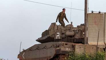 جندي إسرائيلي يسير على برج دبابة قتال "ميركافا مارك 4" متمركزة في موقع على طول الحدود الشمالية مع لبنان (6 نيسان 2023 - أ ف ب).