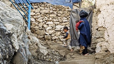امرأة أفغانية ترتدي البرقع تتسلّق مع أطفالها طريقاً صخرياً في كابول (6 نيسان 2023 - أ ف ب).