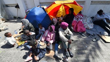 مهاجرون تجمعوا خارج مكاتب المنظمة الدولية للهجرة بعد أن فككت الشرطة التونسية مخيماً موقتاً للاجئين من دول أفريقيا جنوب الصحراء أمام مقر المفوضية السامية للأمم المتحدة لشؤون اللاجئين في تونس (12 نيسان 2023، أ ف ب). 