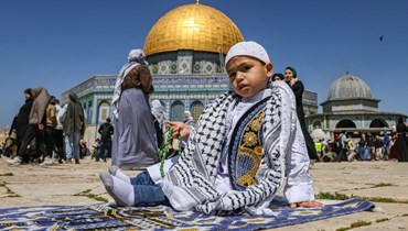 فتى فلسطيني يجلس على سجادة صلاة خارج مسجد قبة الصخرة في المسجد الأقصى  (أ ف ب). 