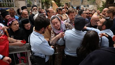 امرأة مسيحية تُخاطب أحد أفراد الشرطة الإسرائيلية عند مدخل البلدة القديمة في القدس المؤدي إلى كنيسة القيامة (15 نيسان 2023 - أ ف ب).