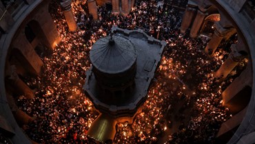 المسيحيون يجتمعون مع الشموع المضاءة بالنور المقدس حول موقع دفن يسوع المسيح في كنيسة القيامة في البلدة القديمة بالقدس (15 نيسان 2023 - أ ف ب).