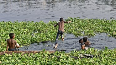 أطفال يستحمون في نهر بوريغانجا في يوم صيفي حار في دكا (19 نيسان 2023، أ ف ب). 