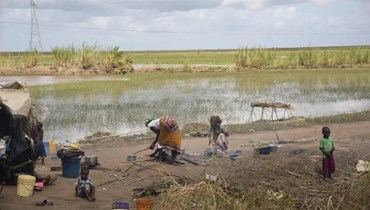 أم تحضر وجبة طعام لعائلتها في مخيم للنازحين على ضفة حقل أرز غمرته المياه قرب قرية نيكوادالا بمقاطعة زامبيزيا في موزمبيق (24 آذار 2023، أ ب). 