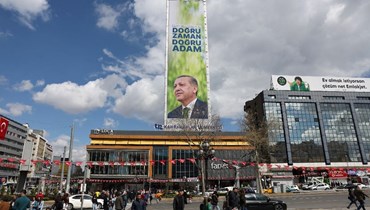 اشخاص يمرون قرب صورة لإردوغان رفعت على مبنى شاهق في أنقرة قبل الانتخابات (21 نيسان 2023، أ ف ب). 