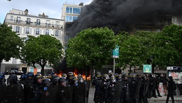  ضباط الشرطة الفرنسية يقفون أمام النار خلال مظاهرة في عيد العمال. (أ ف ب)