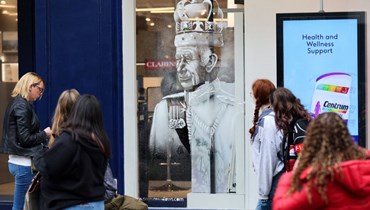 اشخاص يمرون قرب واجهة متجر في وندسور يعرض صورة للملك تشارلز الثالث مصنوعة من رذار الثلج (2 أيار 2023، أ ف ب). 