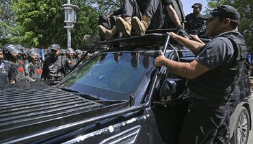 رجال أمن يرافقون سيارة تقل خان لدى وصوله إلى المحكمة العليا في إسلام أباد (9 أيار 2023، أ ف ب).