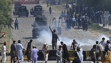 عناصر من الشرطة (في الخلف) يستخدمون الغاز المسيل للدموع لتفريق نشطاء حركة الإنصاف وأنصار خان خلال احتجاج في إسلام أباد على اعتقال زعيمهم (10 أيار 2023، أ ف ب). 