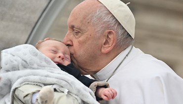 البابا فرانسيس يقبّل طفلاً بينما يترجّل من السيارة البابوية، بعد اللقاء العام الأسبوعي في ساحة القديس بطرس، الفاتيكان (10 أيار 2023 - أ ف ب).