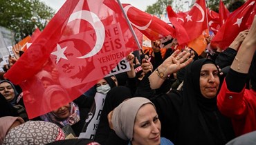 أنصار الرئيس التركي وزعيم حزب العدالة والتنمية، رجب طيب إردوغان، يلوحون بالأعلام الوطنية التركية أثناء حضورهم تجمع حملته في منطقة سلطان غازي (أ ف ب).