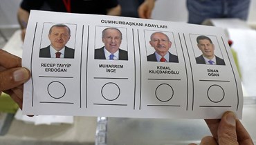 مواطن تركي مقيم في الكويت، يحمل صور المرشحين للرئاسة، أثناء التصويت للانتخابات الرئاسية  (أ ف ب).