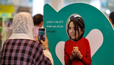 امرأة تصوّر أخرى في معرض طهران الدولي للكتاب (أ ف ب). 