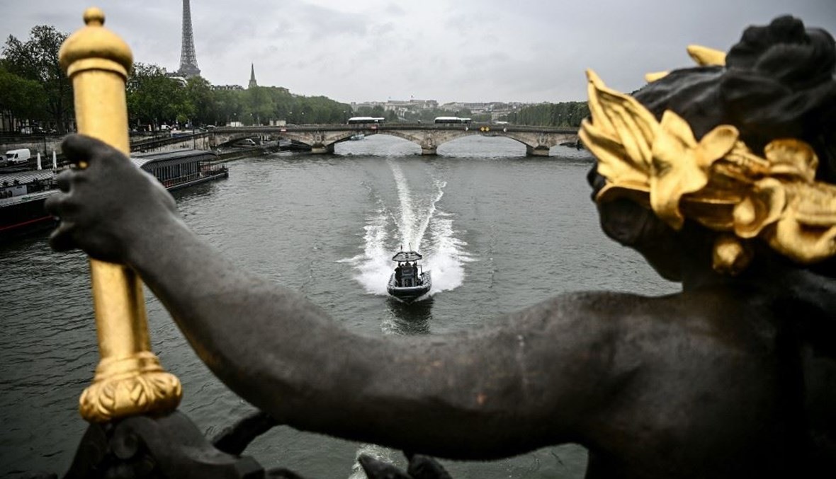 قارب يمر ببرج إيفل وتحت جسر ألكسندر الثالث على نهر السين في باريس (أ ف ب).