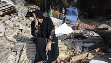  امرأة تجلس وسط أنقاض منزلها في مخيم النصيرات للاجئين في غزة (أ ف ب). 