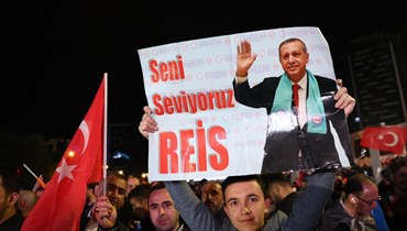 حد مناصري الرئيس التركي رجب طيب إردوغان يحمل ملصقًا كتب عليه "نحن نحبك أيها الرئيس" خارج مقر حزب العدالة والتنمية بعد إغلاق باب الاقتراع في الانتخابات الرئاسية (أ ف ب).