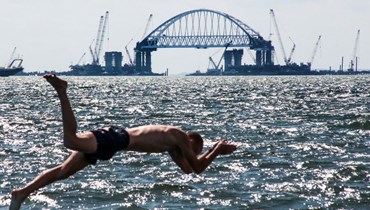  رجل يمارس هواية السباحة أمام موقع بناء قوس سكة حديد لجسر مضيق كيرتش (أ ف ب). 