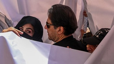 خان (في الوسط) يصل مع زوجته بشرى بيبي (الى اليسار) للمثول أمام محكمة عليا في لاهور (15 أيار 2023، أ ف ب).