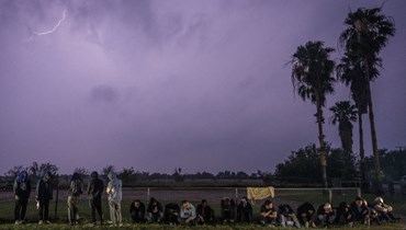  مهاجرون ينتظرون تحت المطر بعد تسليم أنفسهم لدورية الحدود الأميركية بعد عبورهم من المكسيك (أ ف ب).