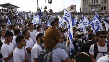 إسرائيليون يلوحون بالأعلام الوطنية يتجمعون خارج باب العامود في البلدة القديمة في القدس خلال "مسيرة العلم" (أ ف ب).